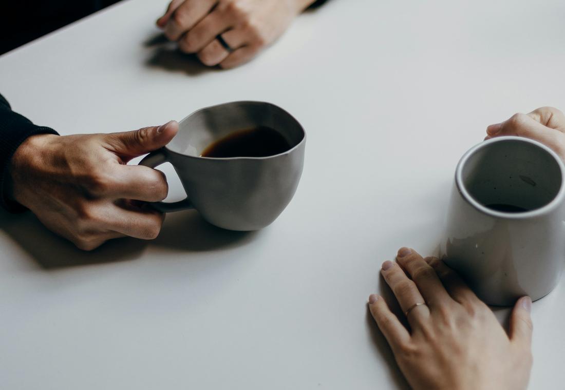 Twee mensen in gesprek aan tafel met een kop koffie
