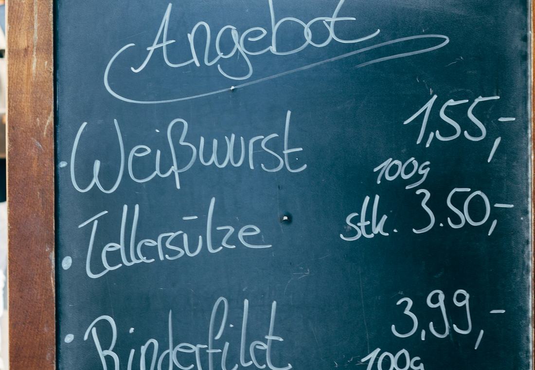 Handgeschreven krijtbord met de prijzen erop, bij een marktkraam